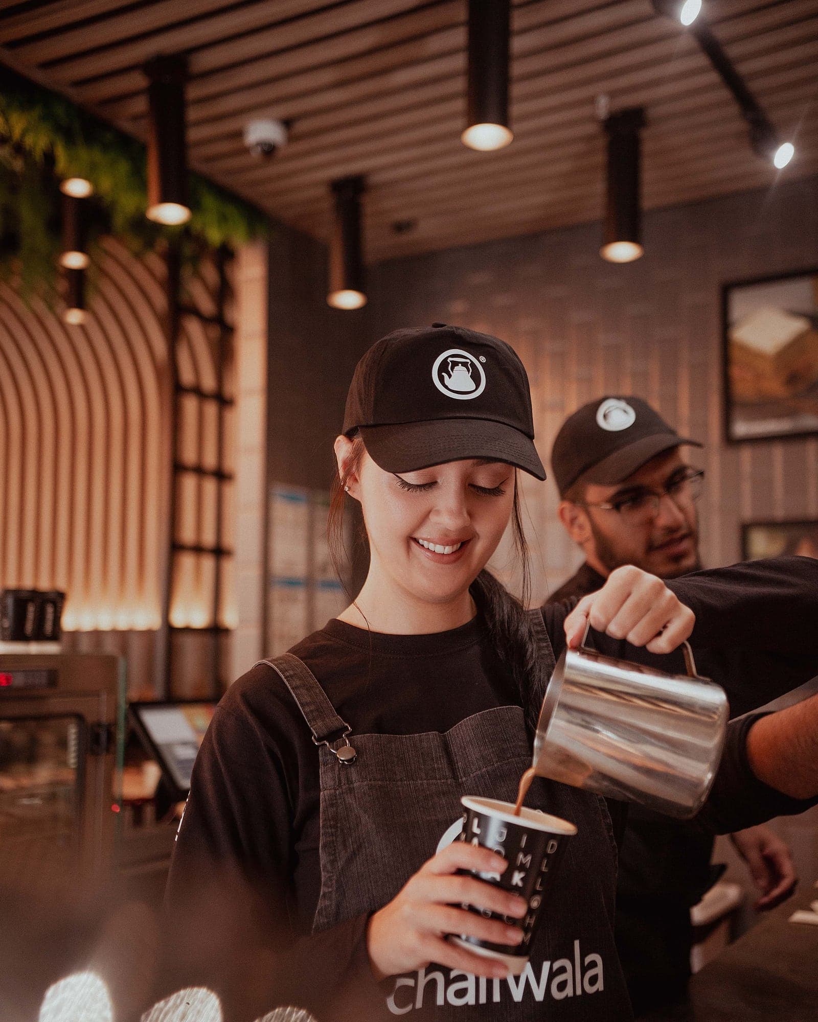 A chaiiwala barista pouring karak chaii